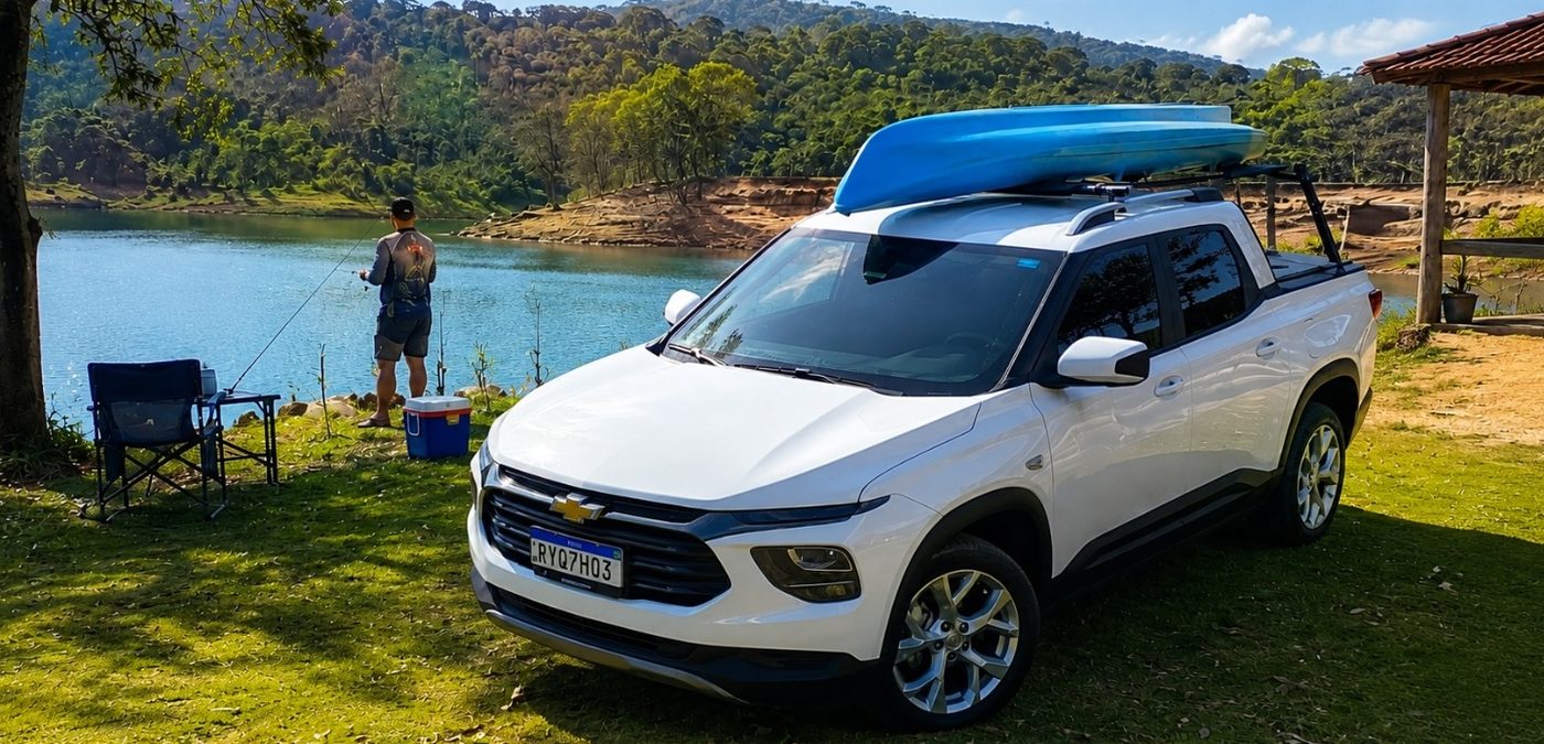 Picape Chevrolet Montana branca com rack de teto transportando um caiaque azul, à beira de um lago.